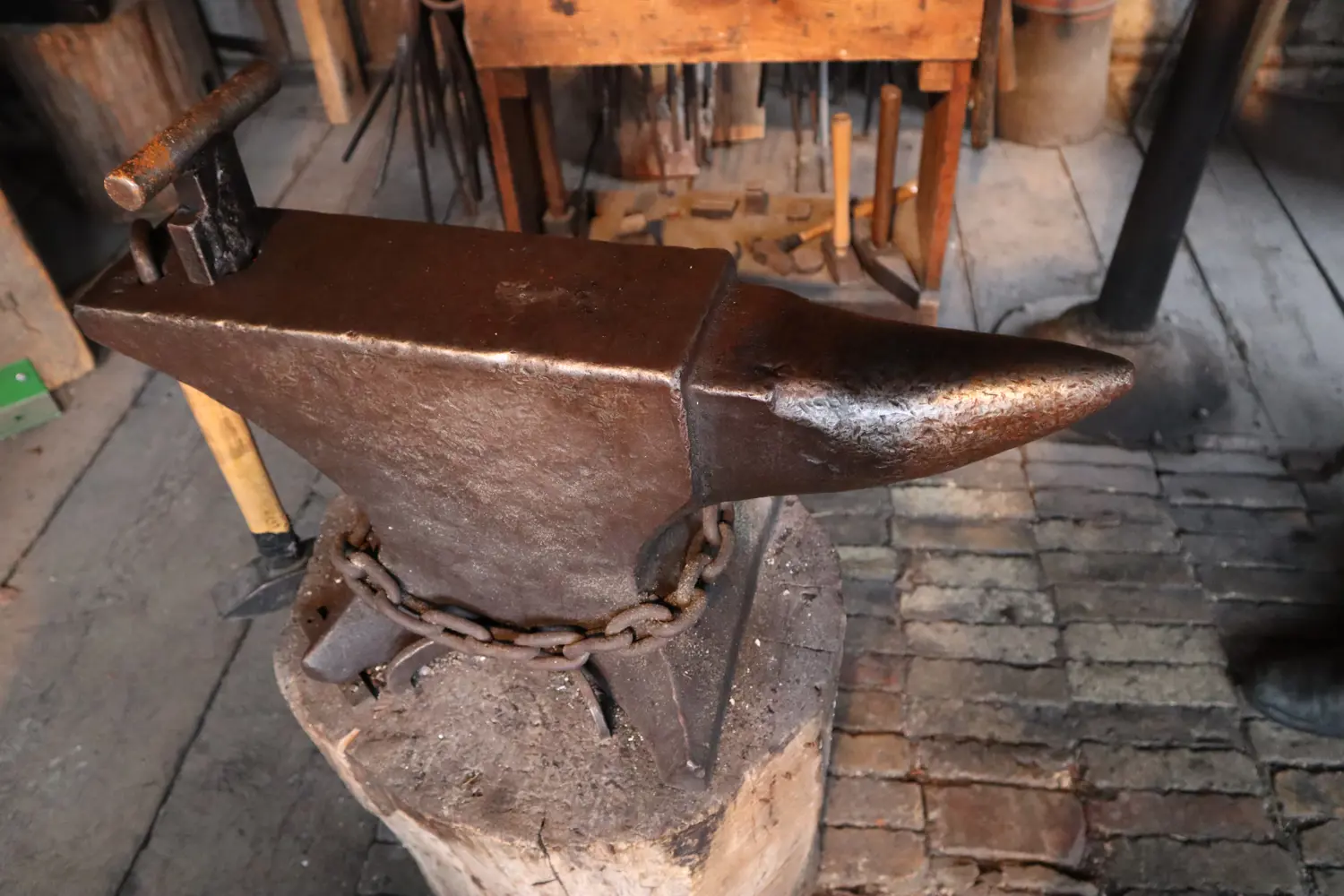 Colour photo of a London pattern anvil with a chain wrapped around the base. One end is squared the other has a horn shaped extension. 