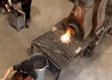 Colour photo of coke or solid forge inside of a modern day blacksmithing studio. An intense flame is visible. 